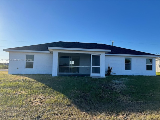 back of house with a lawn, a sunroom, and stucco siding