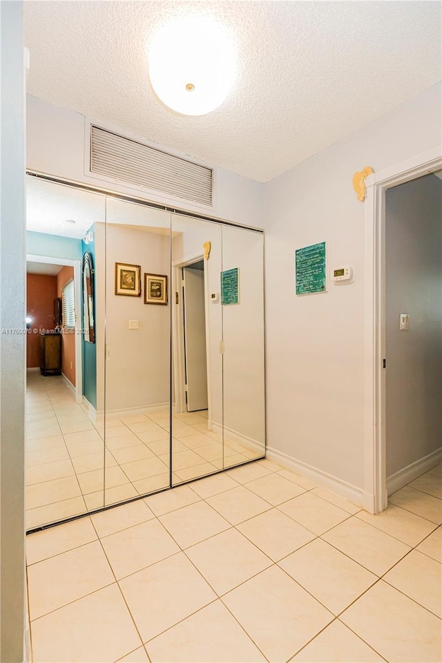 interior space with baseboards, visible vents, a textured ceiling, and light tile patterned flooring