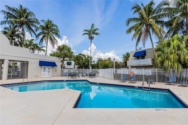 community pool with a patio area and fence