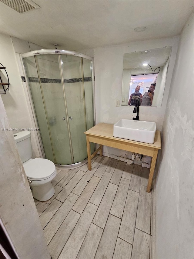 full bathroom with toilet, a sink, visible vents, a shower stall, and wood tiled floor