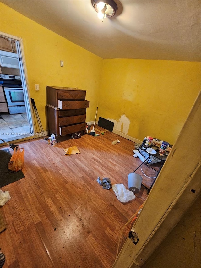 interior space with vaulted ceiling, wood finished floors, and baseboards