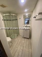 full bath featuring wood finished floors, a shower stall, and toilet