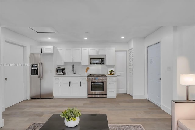 kitchen featuring stainless steel appliances, light countertops, white cabinetry, and a sink