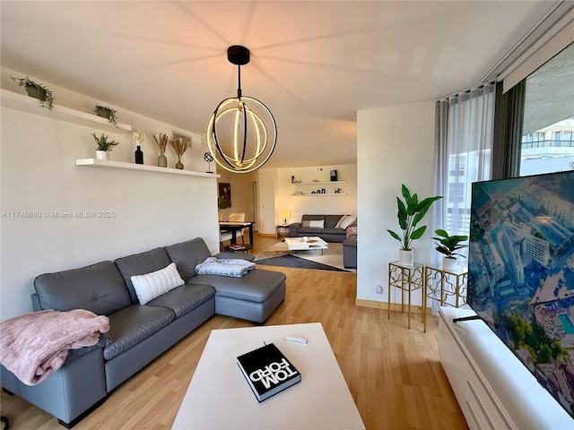 living room featuring a chandelier, light wood-style flooring, and baseboards