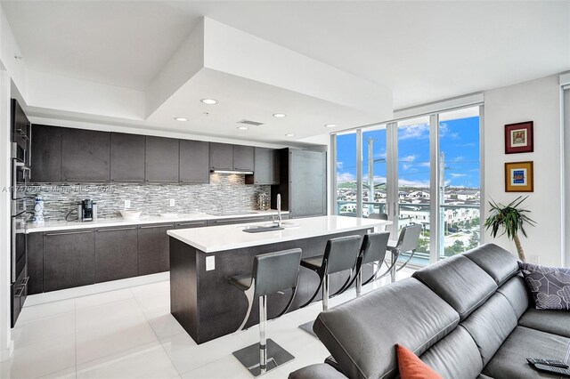 7825 NW 107th Ave Unit 604, Doral, FL 33178 - kitchen featuring open floor plan, a breakfast bar, light countertops, tasteful backsplash, and a sink