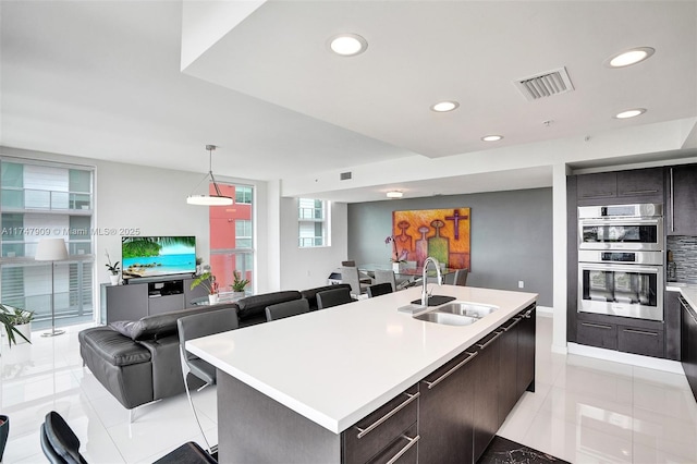 kitchen with visible vents, open floor plan, light countertops, stainless steel double oven, and a sink