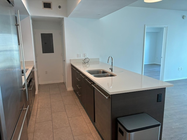 kitchen with stainless steel fridge, electric panel, visible vents, light countertops, and a sink