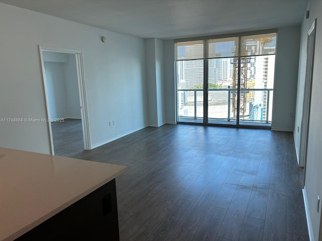 empty room featuring dark wood-style floors, baseboards, and floor to ceiling windows