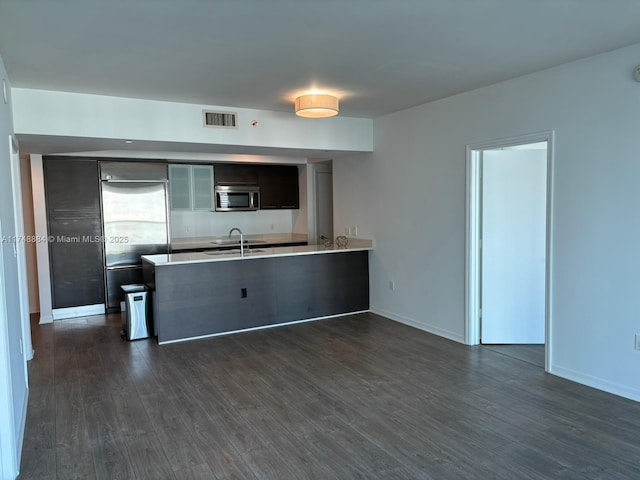 kitchen featuring a peninsula, appliances with stainless steel finishes, dark wood finished floors, and visible vents