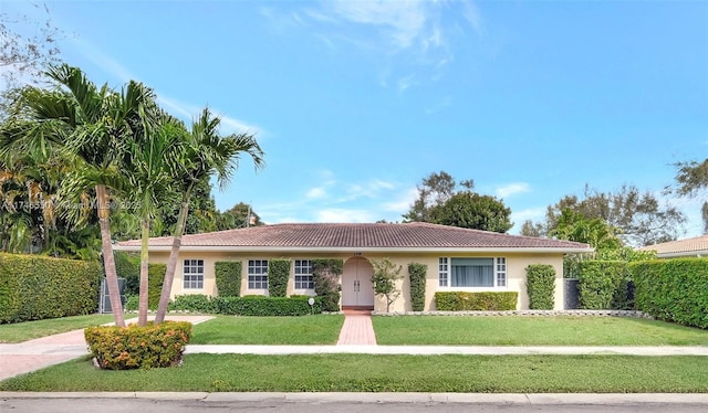 ranch-style house featuring a tile roof, a front lawn, and stucco siding