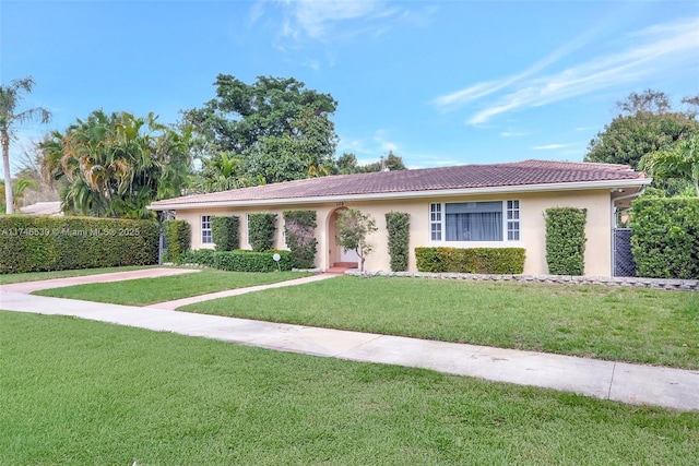 ranch-style home featuring stucco siding, a front lawn, and a tiled roof