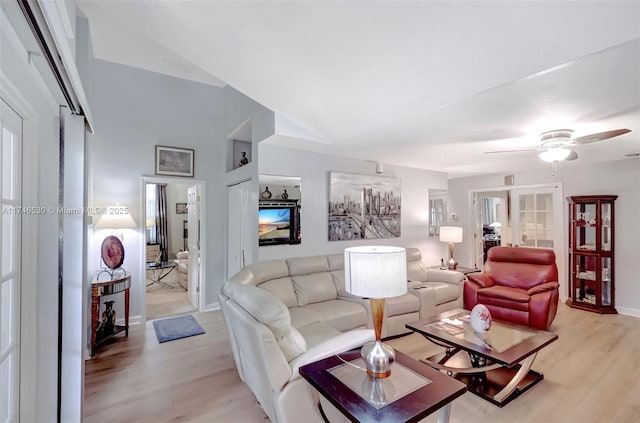 living room with ceiling fan, lofted ceiling, light wood-style flooring, and baseboards