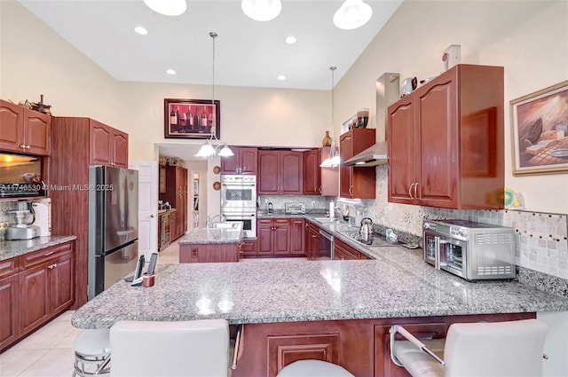 kitchen featuring a peninsula, appliances with stainless steel finishes, pendant lighting, and a breakfast bar area