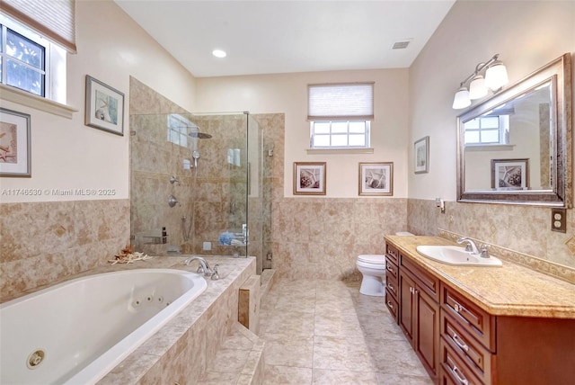 bathroom featuring a stall shower, visible vents, toilet, vanity, and tile walls