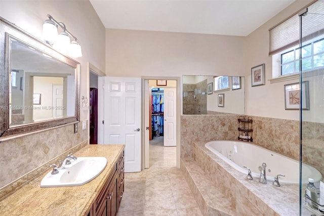 full bath featuring a walk in closet, a stall shower, vanity, tile patterned flooring, and a jetted tub