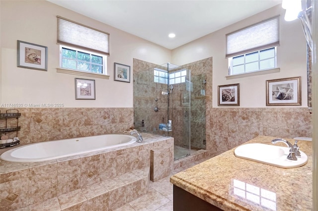 bathroom featuring a garden tub, a shower stall, vanity, and tile walls