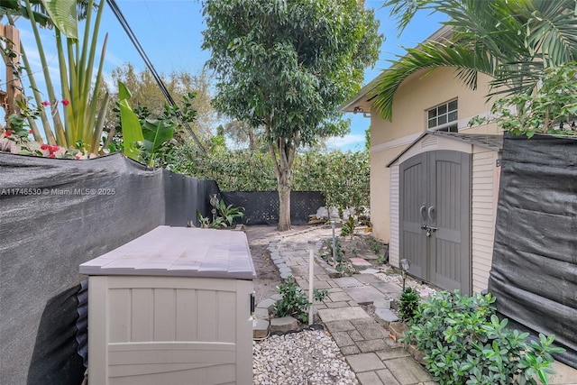 view of patio with an outbuilding, fence, and a storage shed