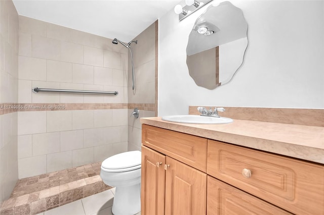 bathroom with tile patterned flooring, tiled shower, vanity, and toilet