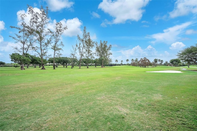 view of property's community with view of golf course and a lawn