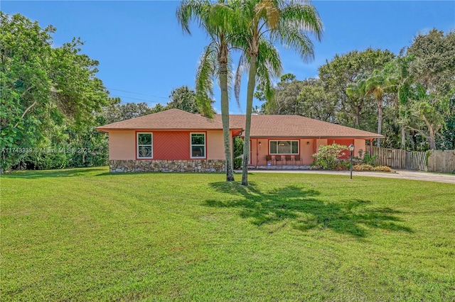 single story home featuring a front yard, stone siding, fence, and stucco siding