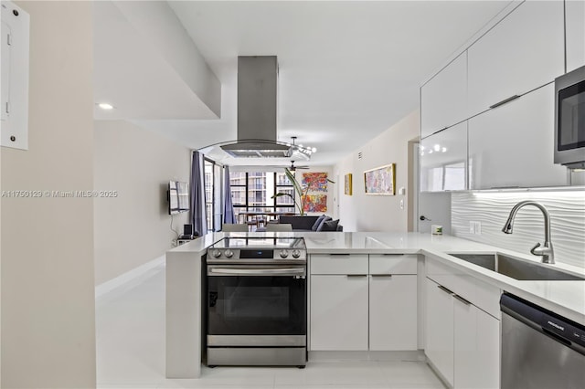 kitchen featuring island exhaust hood, appliances with stainless steel finishes, light countertops, and a sink