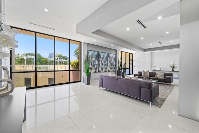 living area featuring light tile patterned flooring, recessed lighting, visible vents, expansive windows, and a raised ceiling