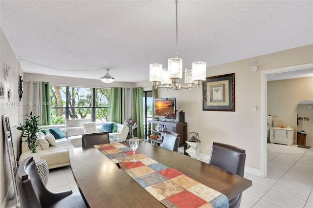 dining area featuring an inviting chandelier, arched walkways, a textured ceiling, and light tile patterned flooring