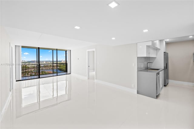 kitchen with a sink, white cabinetry, light countertops, appliances with stainless steel finishes, and modern cabinets