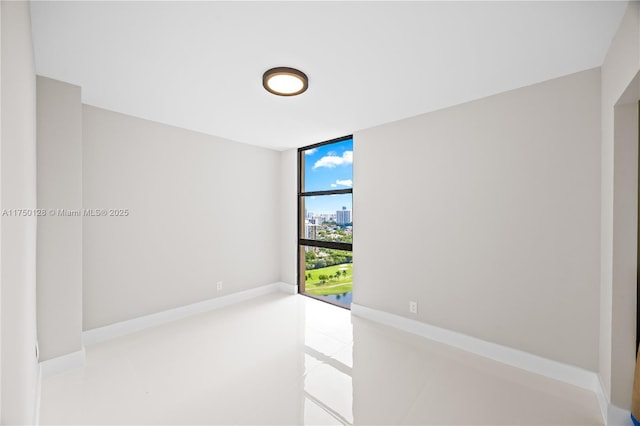 spare room featuring expansive windows and baseboards