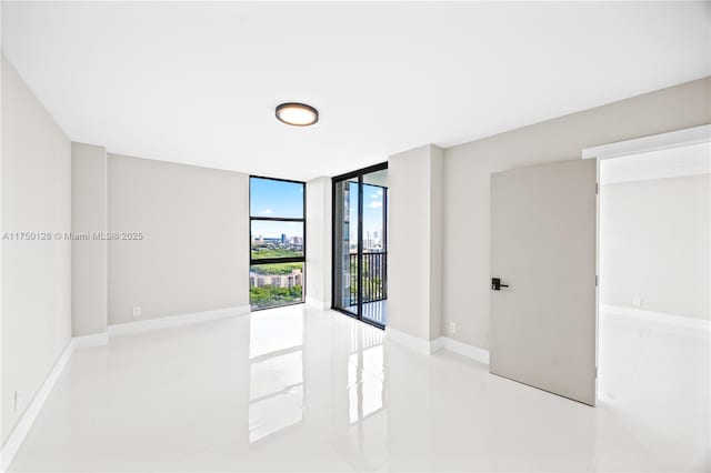 spare room featuring floor to ceiling windows and baseboards