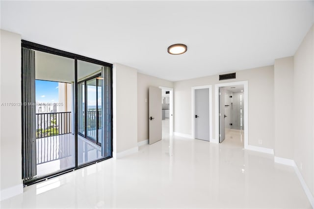 unfurnished room featuring floor to ceiling windows, visible vents, and baseboards