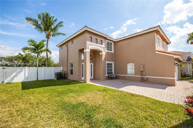 rear view of house featuring a yard, a patio area, fence, and stucco siding