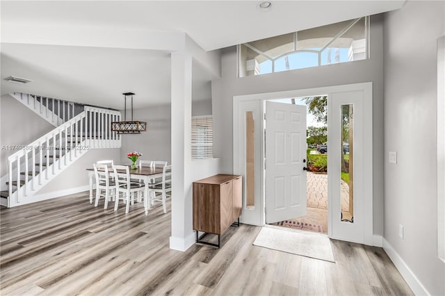 foyer with baseboards, visible vents, stairway, and light wood finished floors