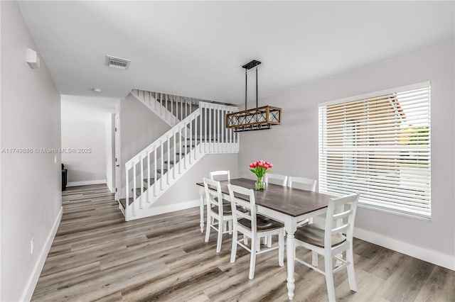 dining room featuring baseboards, stairs, visible vents, and wood finished floors