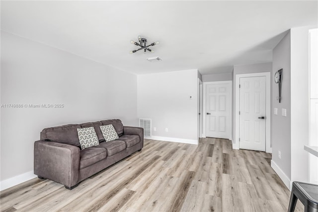 living room featuring light wood-type flooring, visible vents, and baseboards