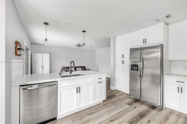 kitchen featuring white cabinets, appliances with stainless steel finishes, light countertops, and a sink