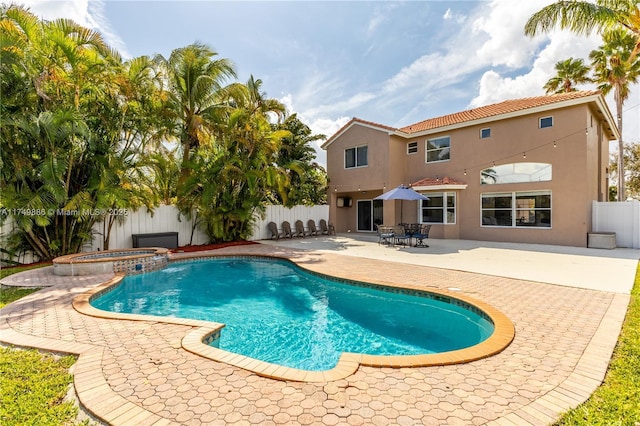 view of swimming pool featuring a fenced backyard, a pool with connected hot tub, and a patio