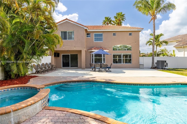 view of swimming pool featuring a patio area, a pool with connected hot tub, fence, and cooling unit