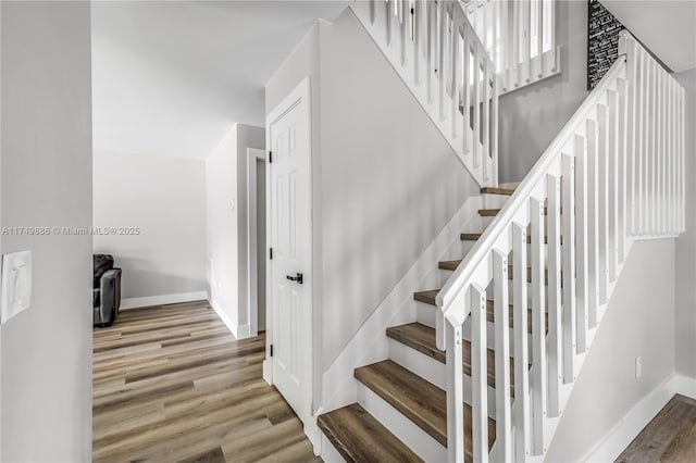 stairs with wood finished floors and baseboards