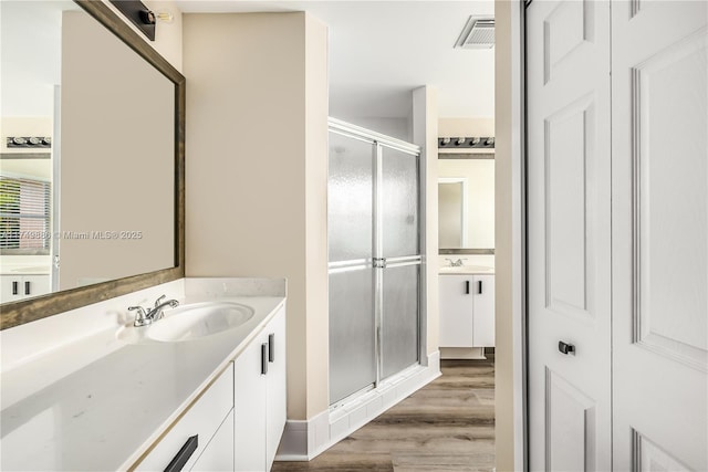 full bathroom featuring wood finished floors, a stall shower, vanity, and visible vents