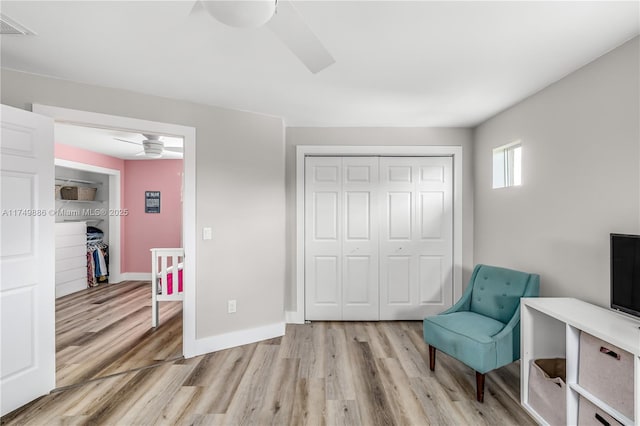 sitting room with baseboards, ceiling fan, visible vents, and light wood finished floors