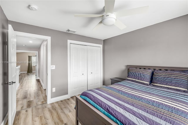 bedroom featuring baseboards, visible vents, a ceiling fan, light wood-style flooring, and a closet