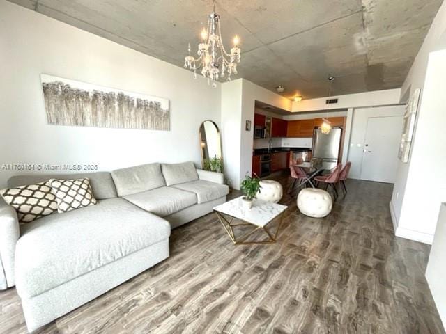 living area featuring baseboards, wood finished floors, visible vents, and an inviting chandelier