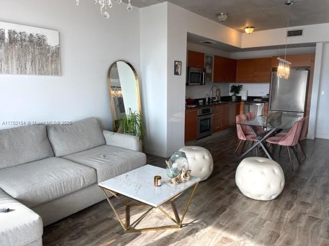 living room featuring a chandelier, dark wood-style flooring, and visible vents