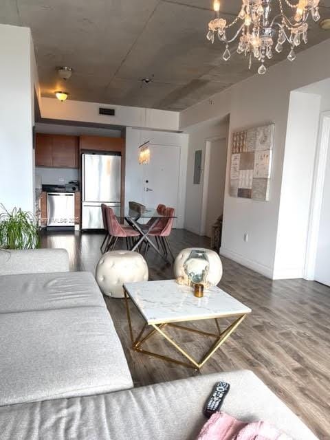 living room featuring an inviting chandelier, visible vents, and wood finished floors