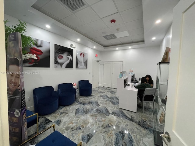 interior space with a drop ceiling, recessed lighting, visible vents, marble finish floor, and a tray ceiling