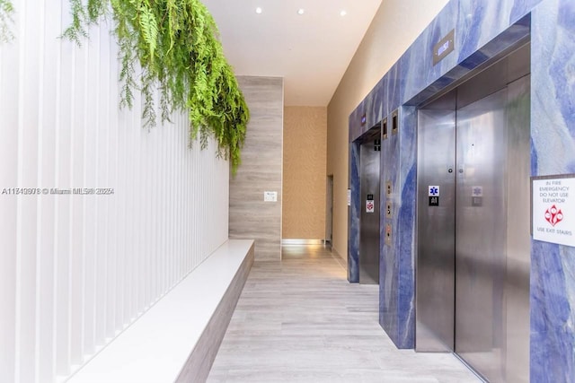 corridor featuring elevator and light wood-style flooring