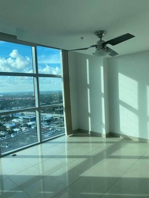 tiled empty room with floor to ceiling windows and baseboards