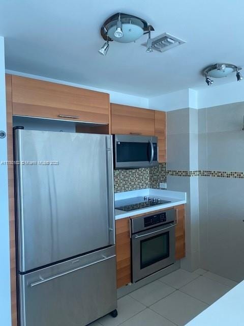 kitchen featuring light tile patterned floors, visible vents, brown cabinetry, appliances with stainless steel finishes, and light countertops