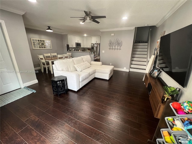 living room featuring a ceiling fan, stairs, ornamental molding, and dark wood-style flooring